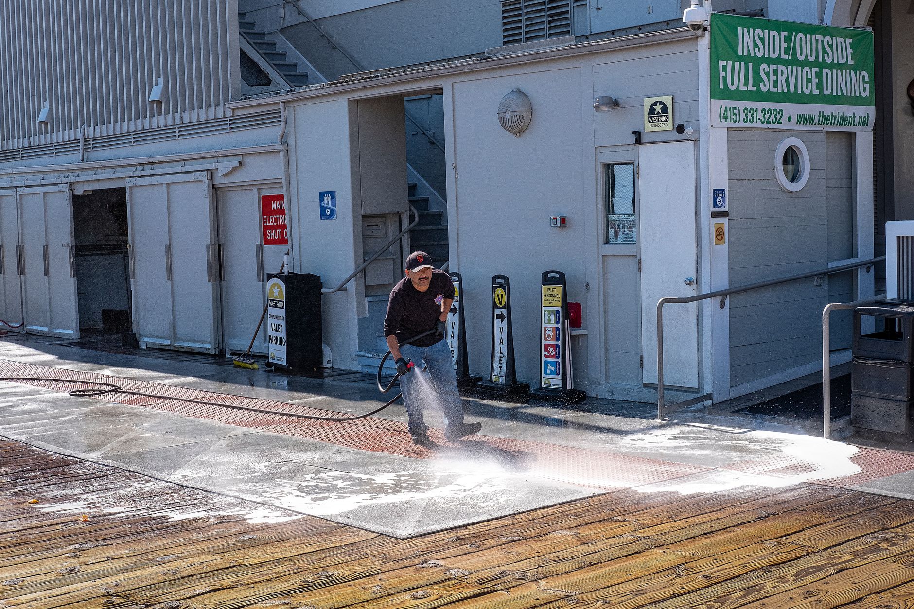 A professional pressure washing technician in safety gear cleaning the exterior wall of a modern commercial office building
